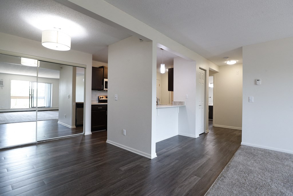 an empty living room and kitchen with wood floors and white walls