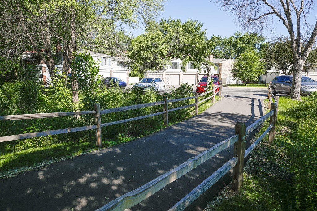 a street with a fence and cars parked in front of houses