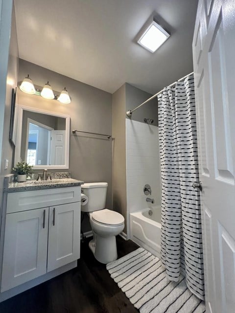 A white bathroom with a toilet, sink, and shower.