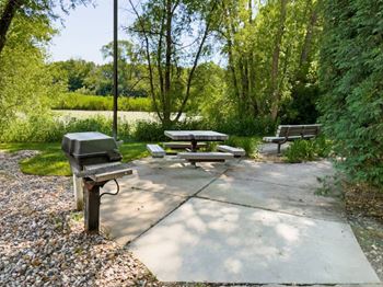 two picnic tables and benches in a park next to a river