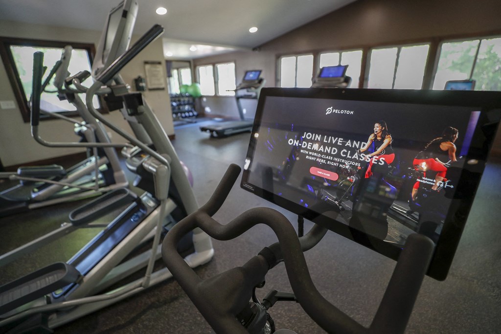 a gym with cardio equipment and a screen on the floor