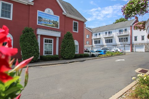 A red building with a sign on it and a blue car parked in front.