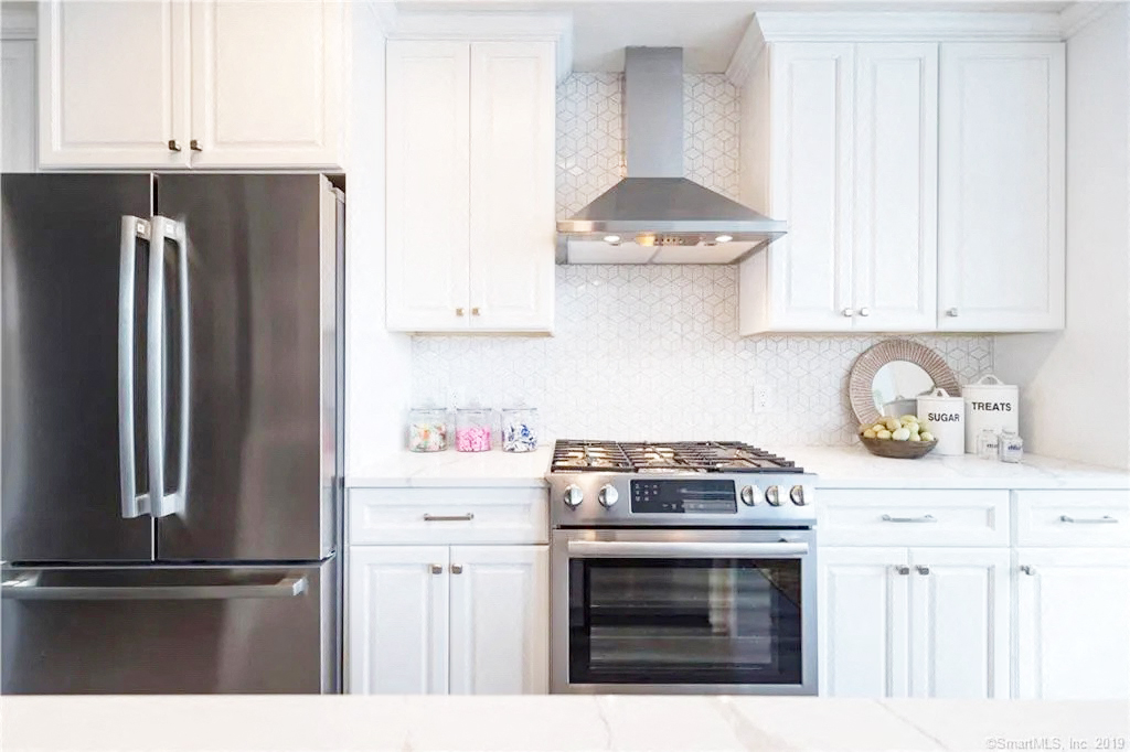 a white kitchen with stainless steel appliances and white cabinets