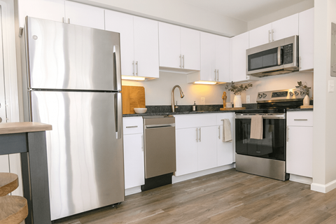 A modern kitchen with a stainless steel refrigerator and white cabinets.