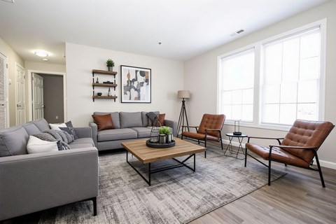 A living room with a grey sofa, a brown leather chair, and a wooden coffee table.