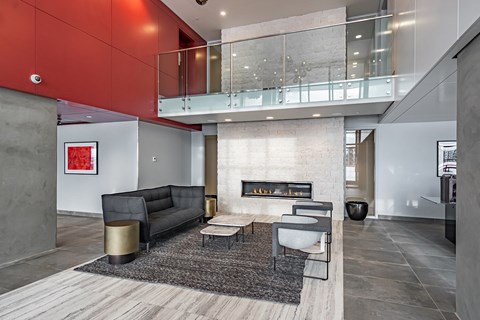 A modern living room with a black couch and a fireplace.