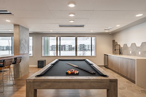 A pool table with a black cloth and white balls is in the center of the room.