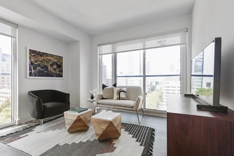 A living room with a black chair, a white chair, a wooden coffee table, and a painting on the wall.