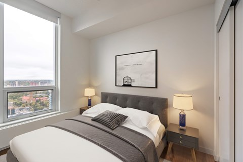A bedroom with a large bed and a window overlooking a cityscape.