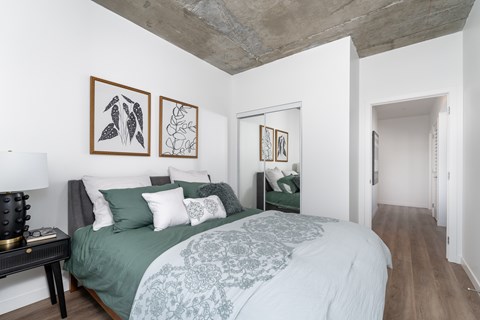 A bedroom with a bed, nightstand, and two pictures on the wall.