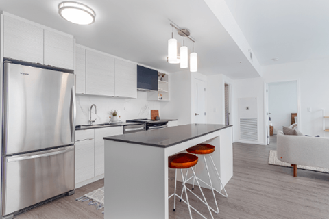 A modern kitchen with a stainless steel refrigerator and a central island with bar stools.