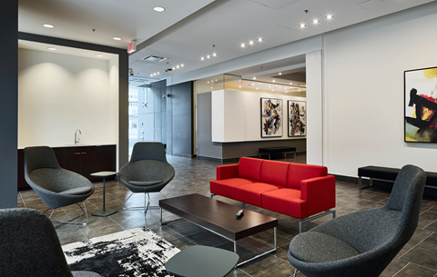A living room with a red couch and grey chairs.