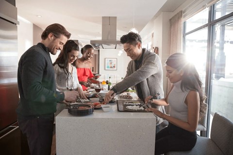 A group of people are gathered around a counter in a brightly lit room.