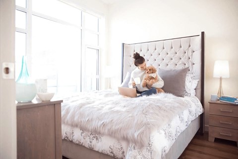 A woman is sitting on a bed with a teddy bear.