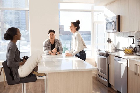 Three people are sitting at a kitchen island.