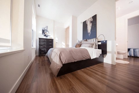 A bedroom with a large bed, a dresser, and a painting on the wall.