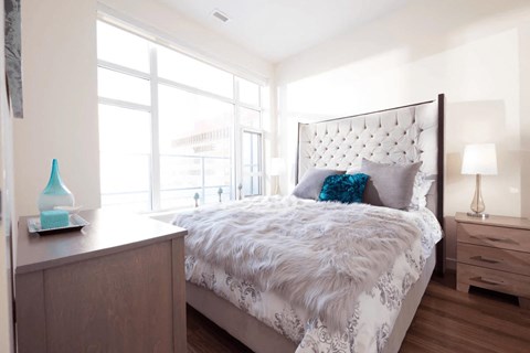 A bedroom with a large bed, a nightstand, and a window.