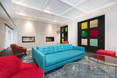 A blue couch sits in a living room with a glass table in front of it.