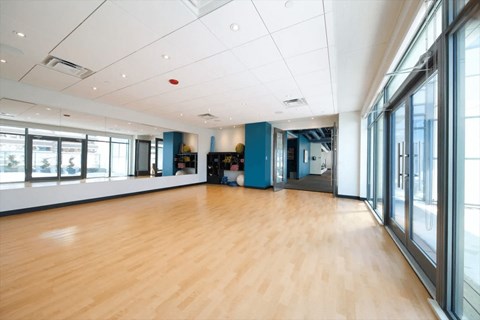 A spacious room with wooden floors and large windows.