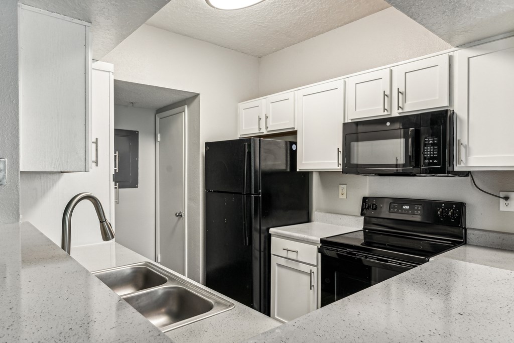 A kitchen with black appliances and white cabinets.