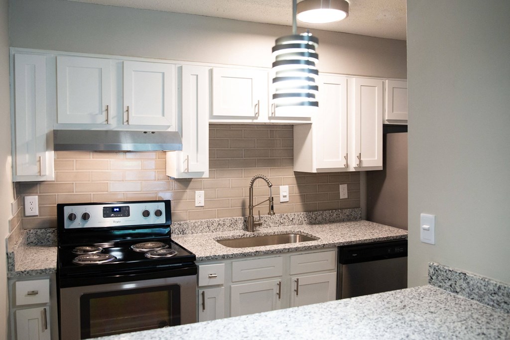 a kitchen with white cabinets and granite counter tops and a sink