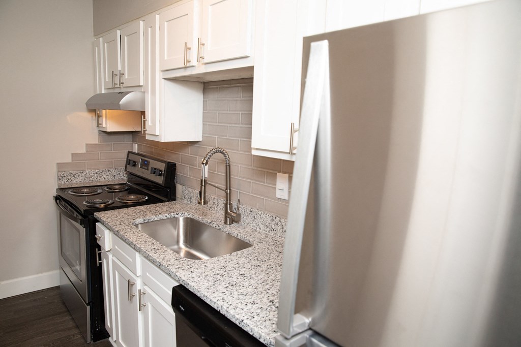 a kitchen with white cabinets and a sink and a refrigerator