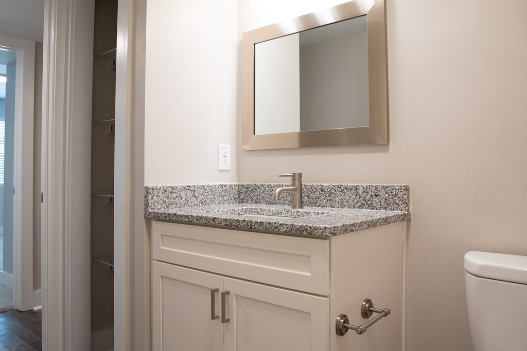a bathroom with granite counter top and a sink and mirror