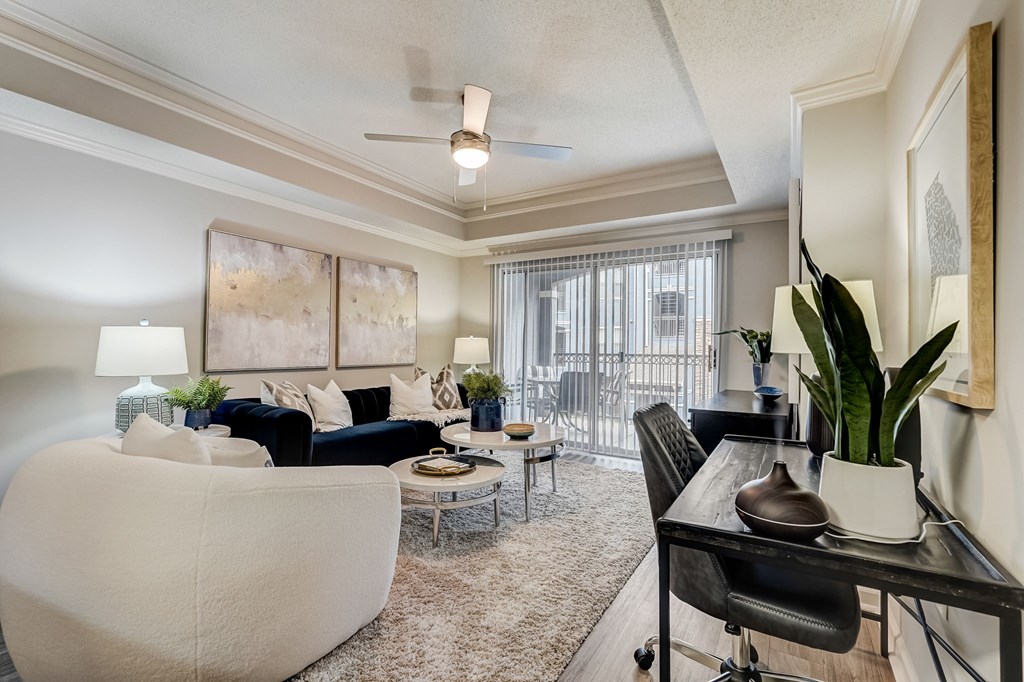 A living room with a white couch, a black chair, and a table with a plant on it.