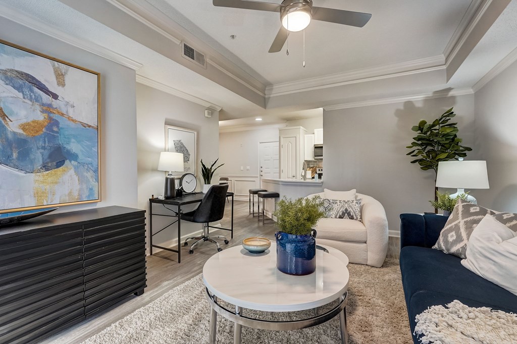 A living room with a blue couch, a coffee table, and a painting on the wall.