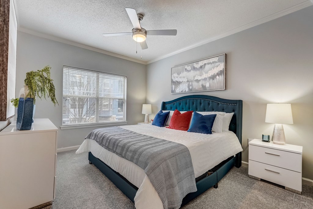 A bedroom with a bed, nightstand, and a ceiling fan.