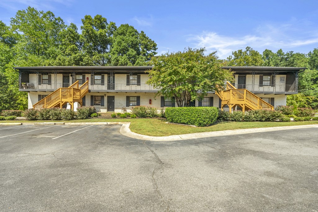 A parking lot in front of a two-story building with a balcony.