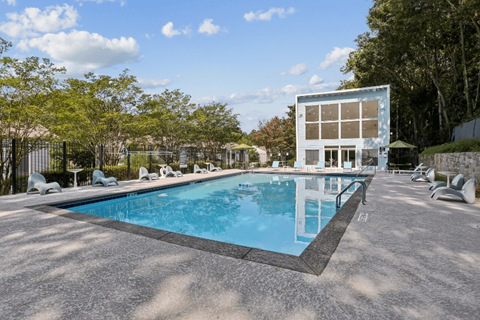 A large swimming pool with a blue water and a white building near it.