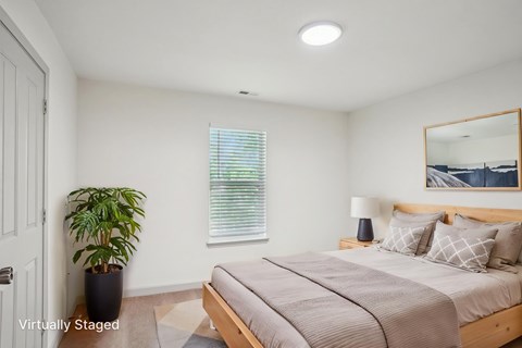 A bedroom with a bed, a potted plant, and a mirror.