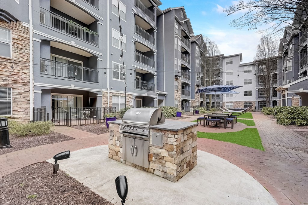 A stone fireplace sits in the middle of a courtyard between apartment buildings.