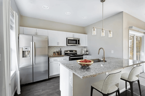 A modern kitchen with a granite countertop and stainless steel appliances.