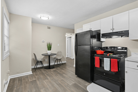A kitchen with black appliances and a round table with two chairs.