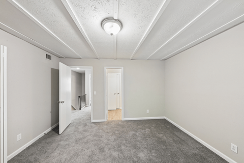 A spacious room with a carpeted floor and a ceiling light.