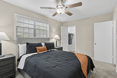 A bedroom with a bed, nightstand, and a ceiling fan.