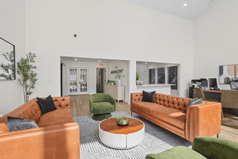 A living room with orange couches and green chairs.