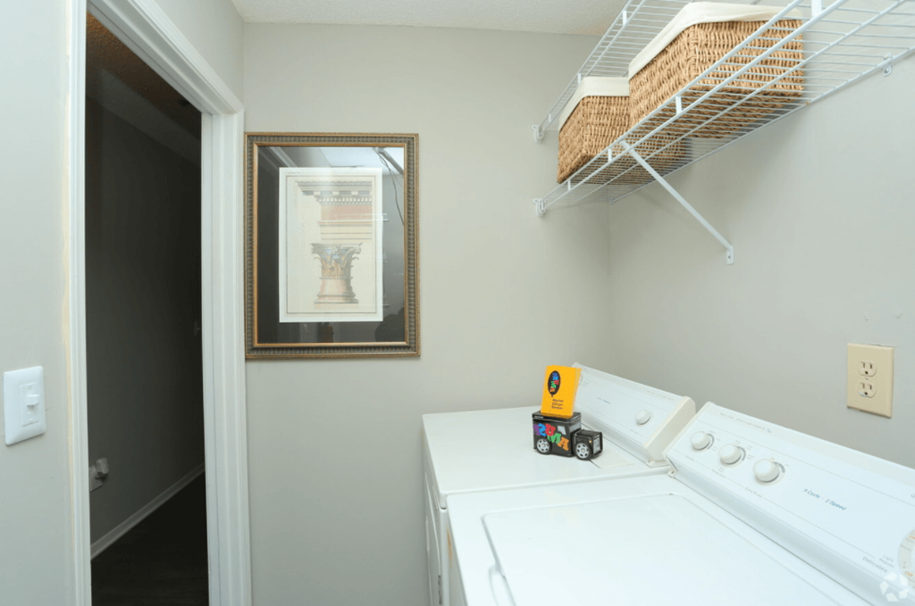 a laundry room with a washer and dryer and a shelf on the wall