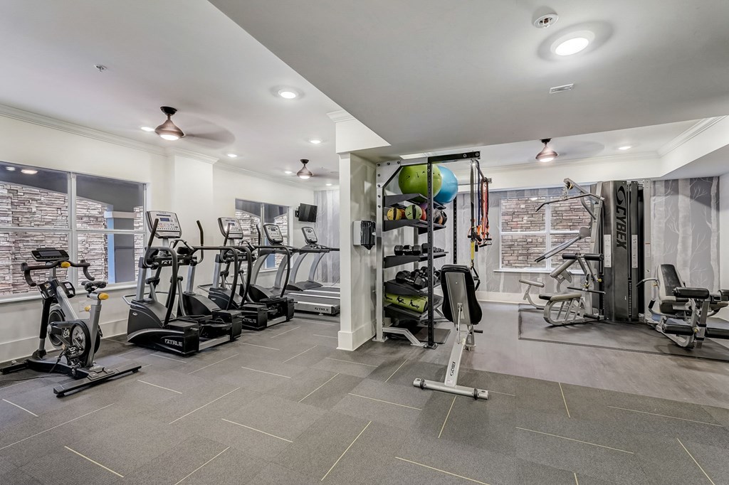 A spacious gym with a variety of equipment including treadmills, stationary bikes, and weight machines.