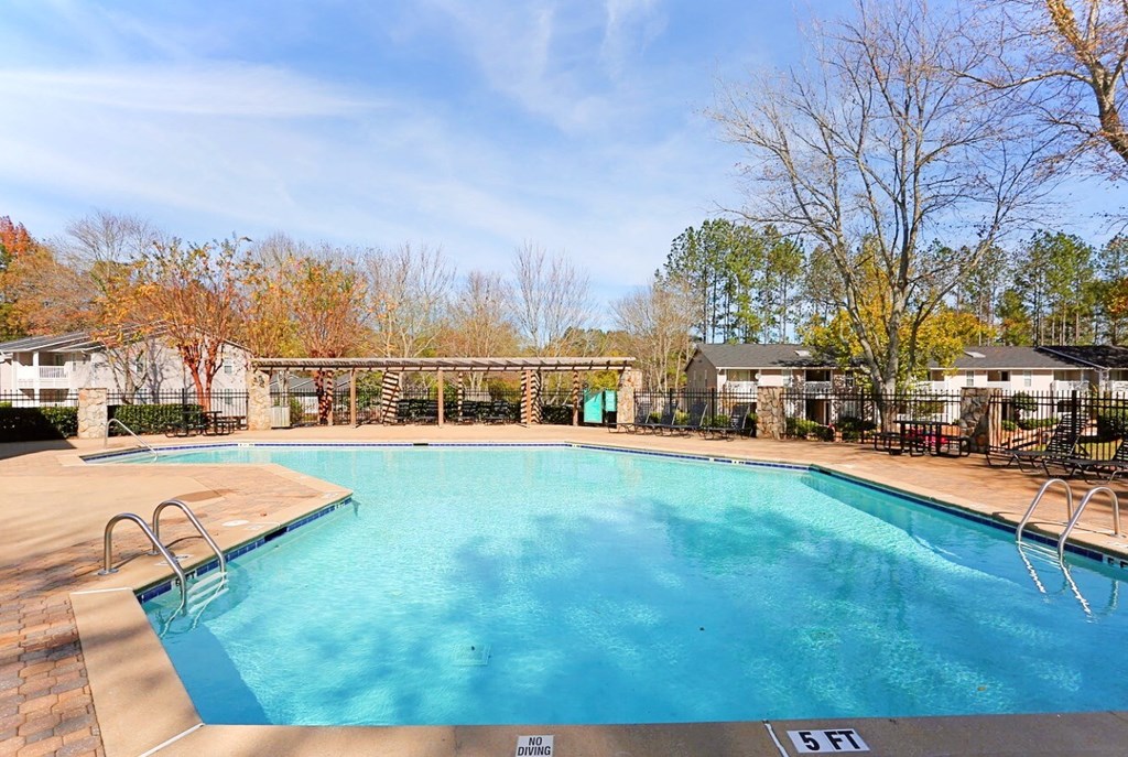 a swimming pool with trees and a house in the background