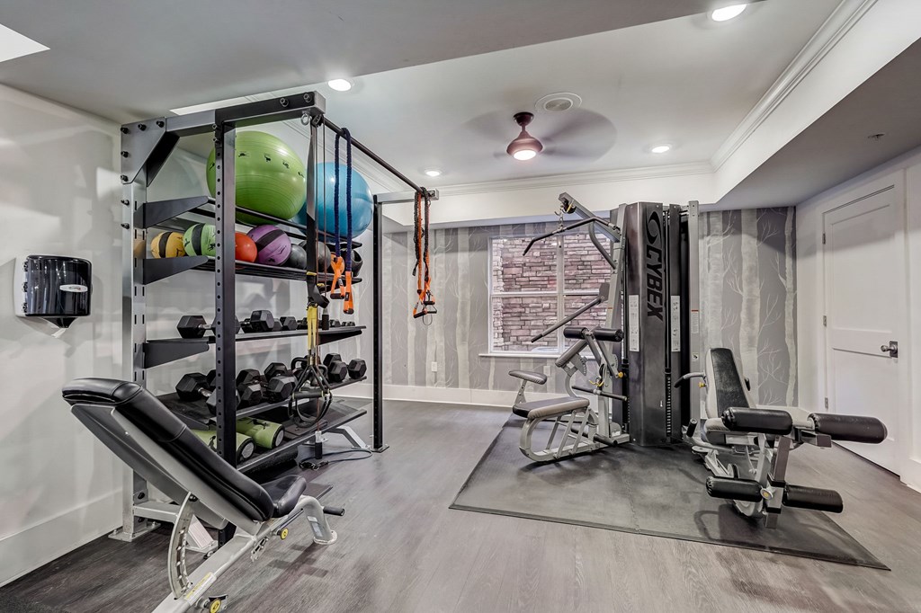 A home gym with a variety of equipment including a weight bench, a squat rack, and a stationary bike.