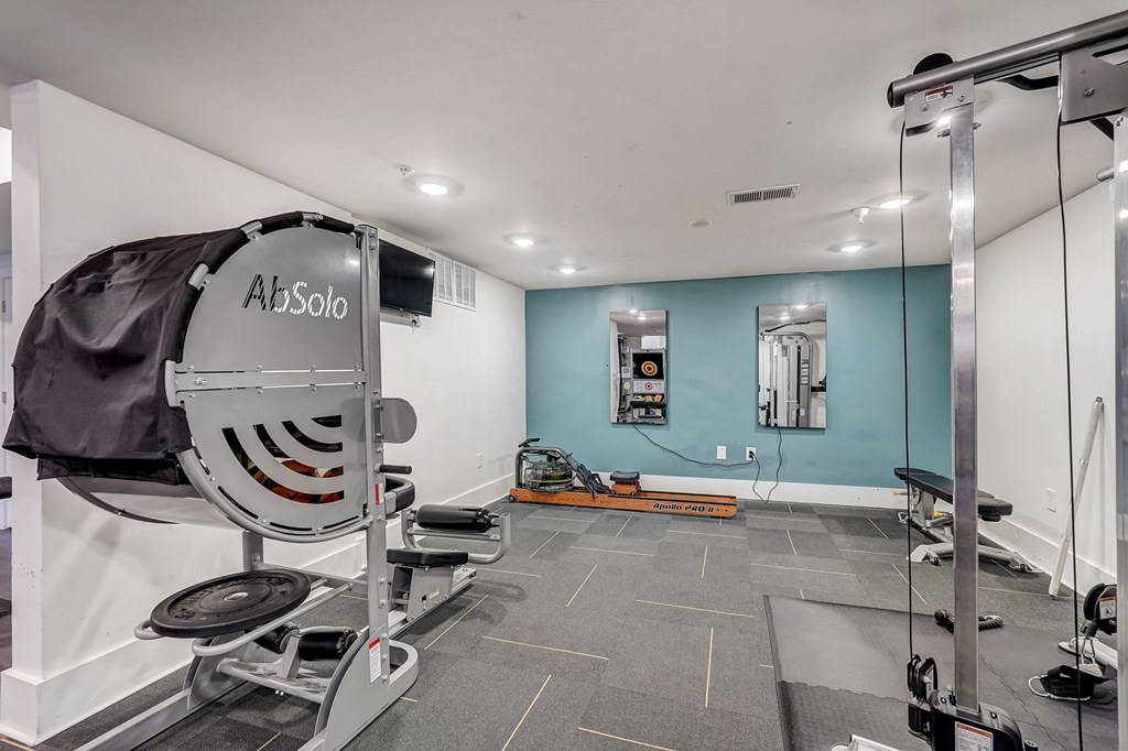 A gym with a rowing machine and a weight rack.