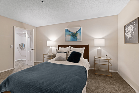 A bedroom with a bed, nightstands, and a painting on the wall.