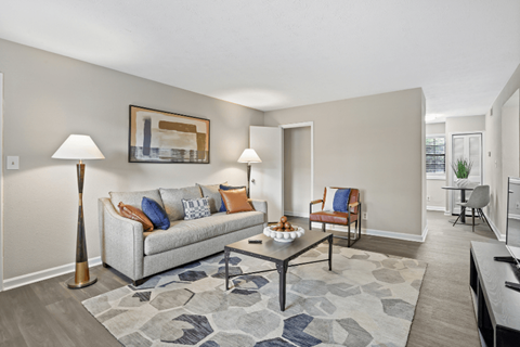 A living room with a grey couch, a coffee table, and a lamp.