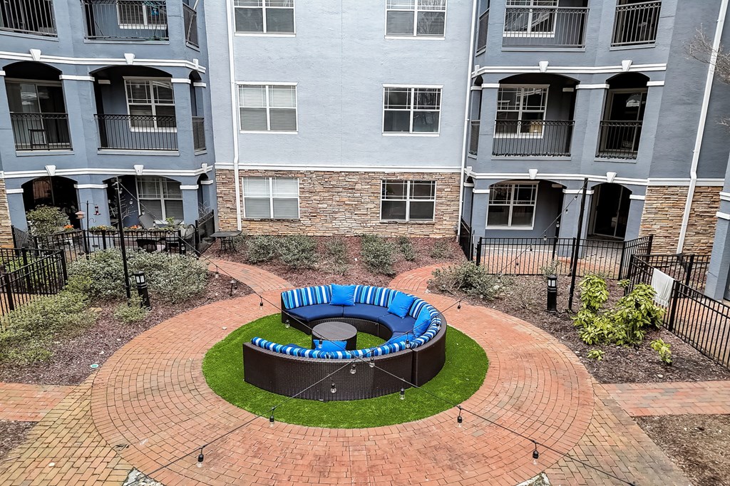 A roundabout with a blue and white striped fence in the middle of a courtyard surrounded by apartment buildings.