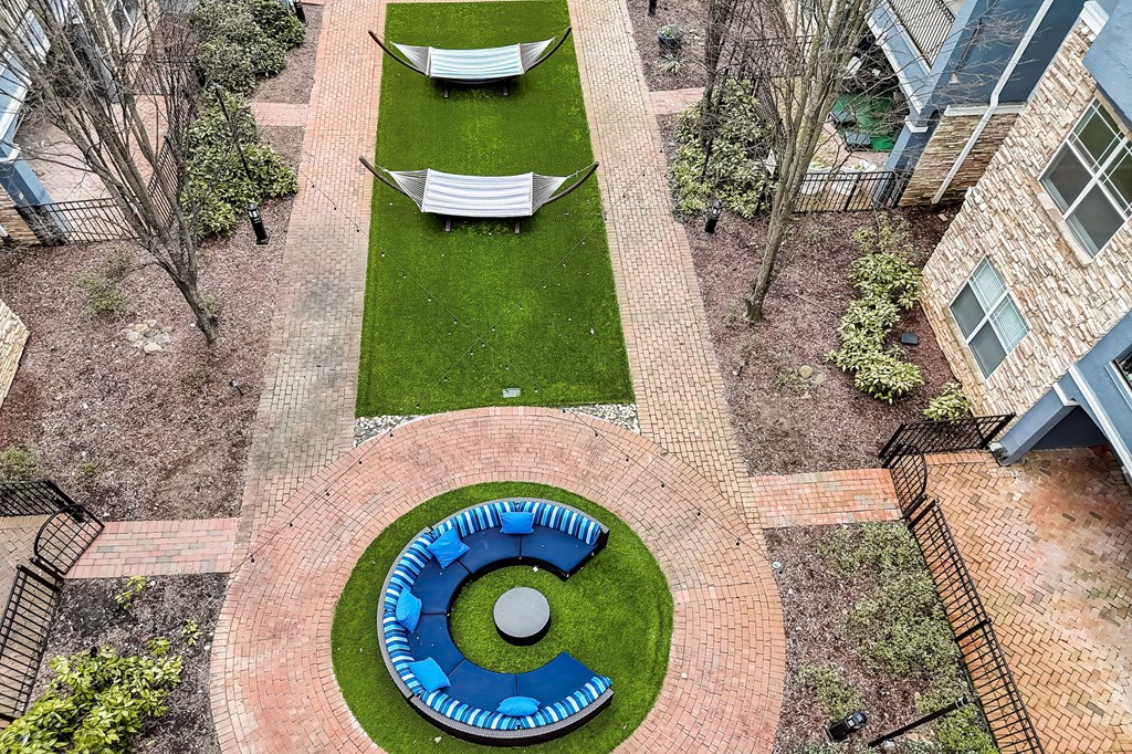 A circular brick structure with a blue border is surrounded by a brick walkway and a grassy area.