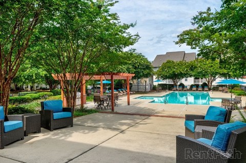 A pool area with a gazebo and lounge chairs.