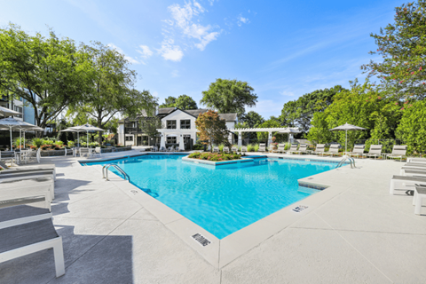 A large swimming pool surrounded by lounge chairs and trees.